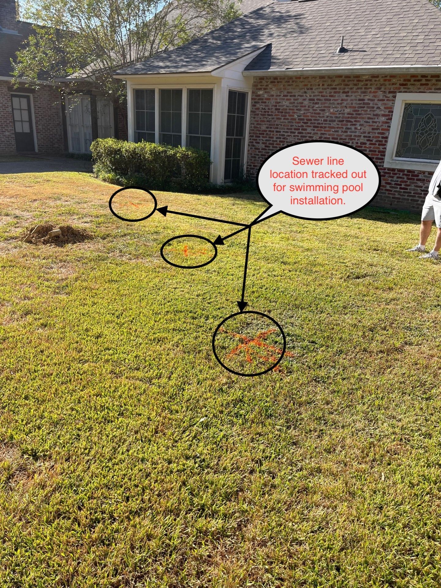 Lawn with three patches of disturbed earth, likely marking a buried cable, in front of a house.