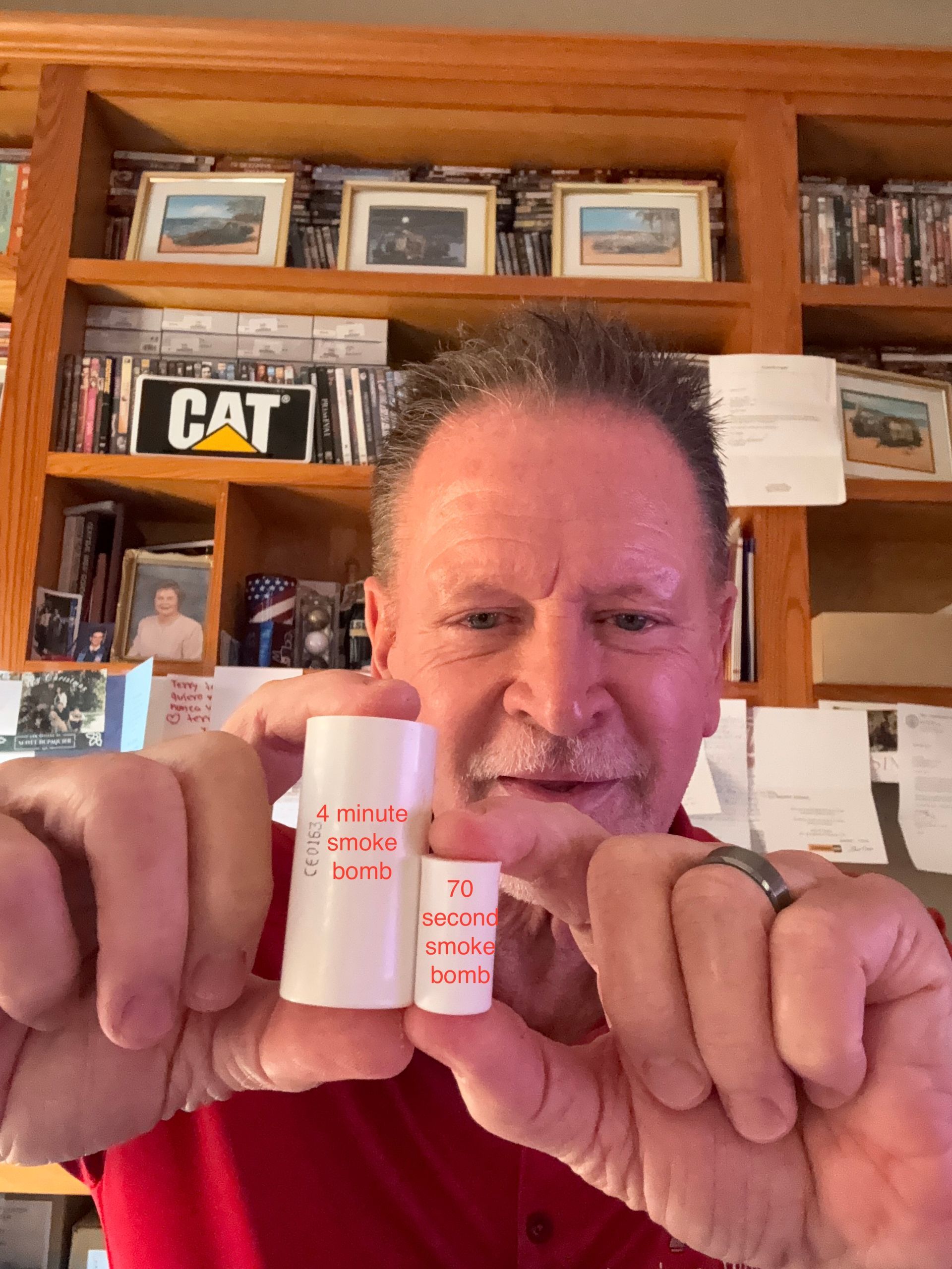 Man holding two pink-and-white prescription bottles in front of a wooden bookshelf