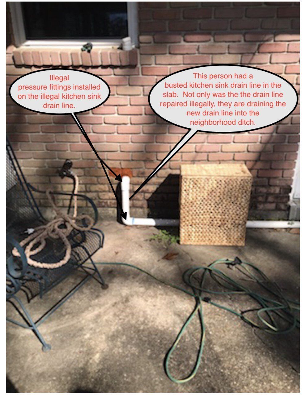 Exterior view: person replacing a drain line on a brick wall, with hoses and chair present.