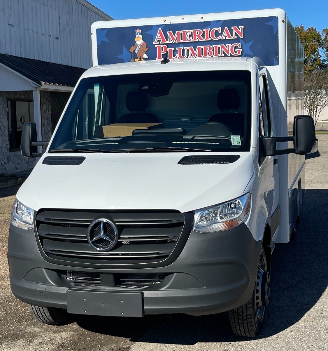 White American Plumbing service van parked outside a building, front view.