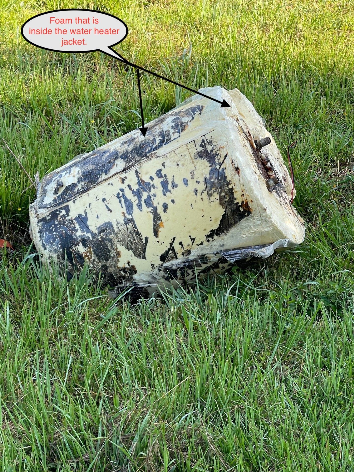 A damaged yellow container on green grass with visible foam inside.