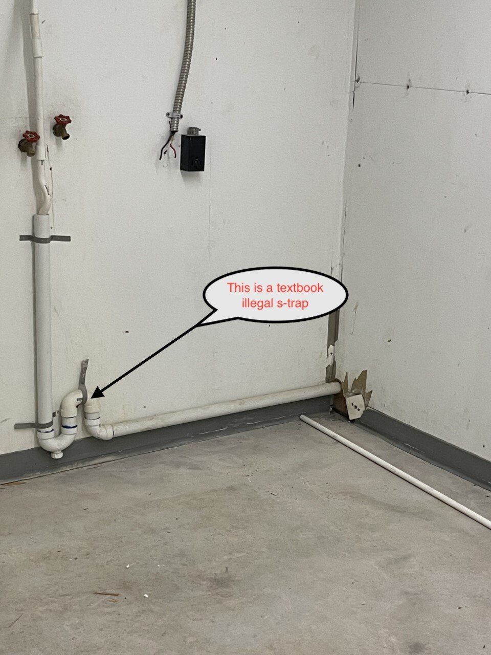 A corner of a room with exposed white plumbing pipes, with a textbox pointing to the pipes.