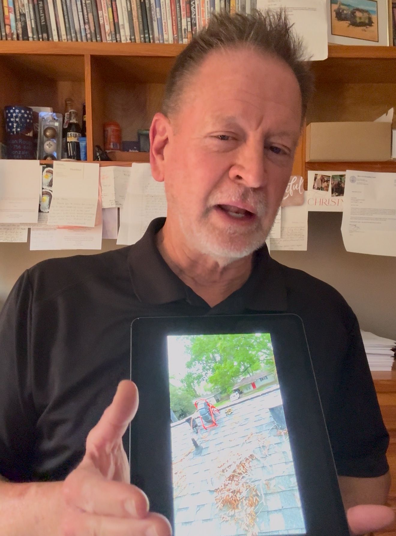 Man holding a tablet with a colorful map displayed, standing in a home office.