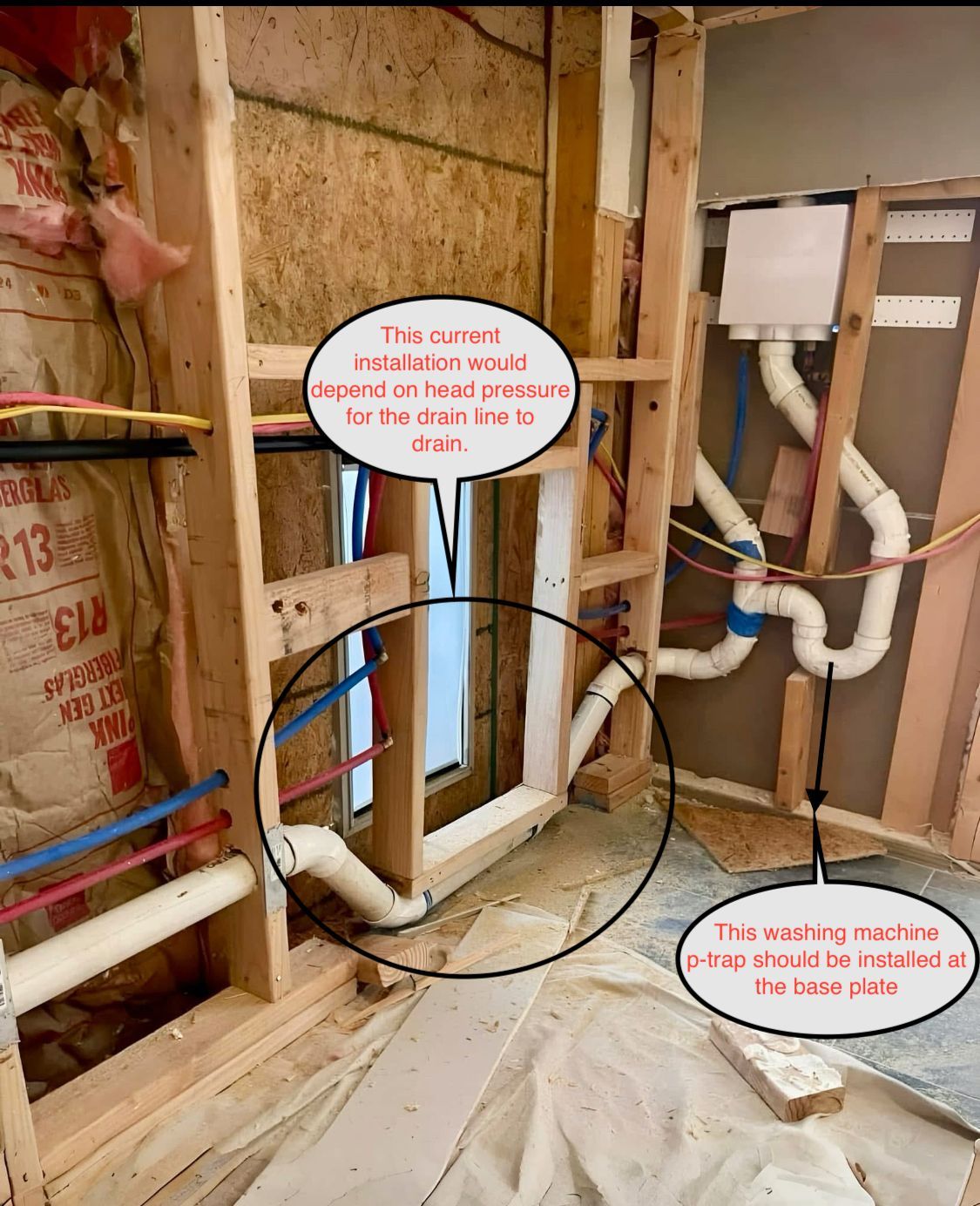 Framed wall with exposed plumbing and ductwork under construction, with red and blue pipes visible.