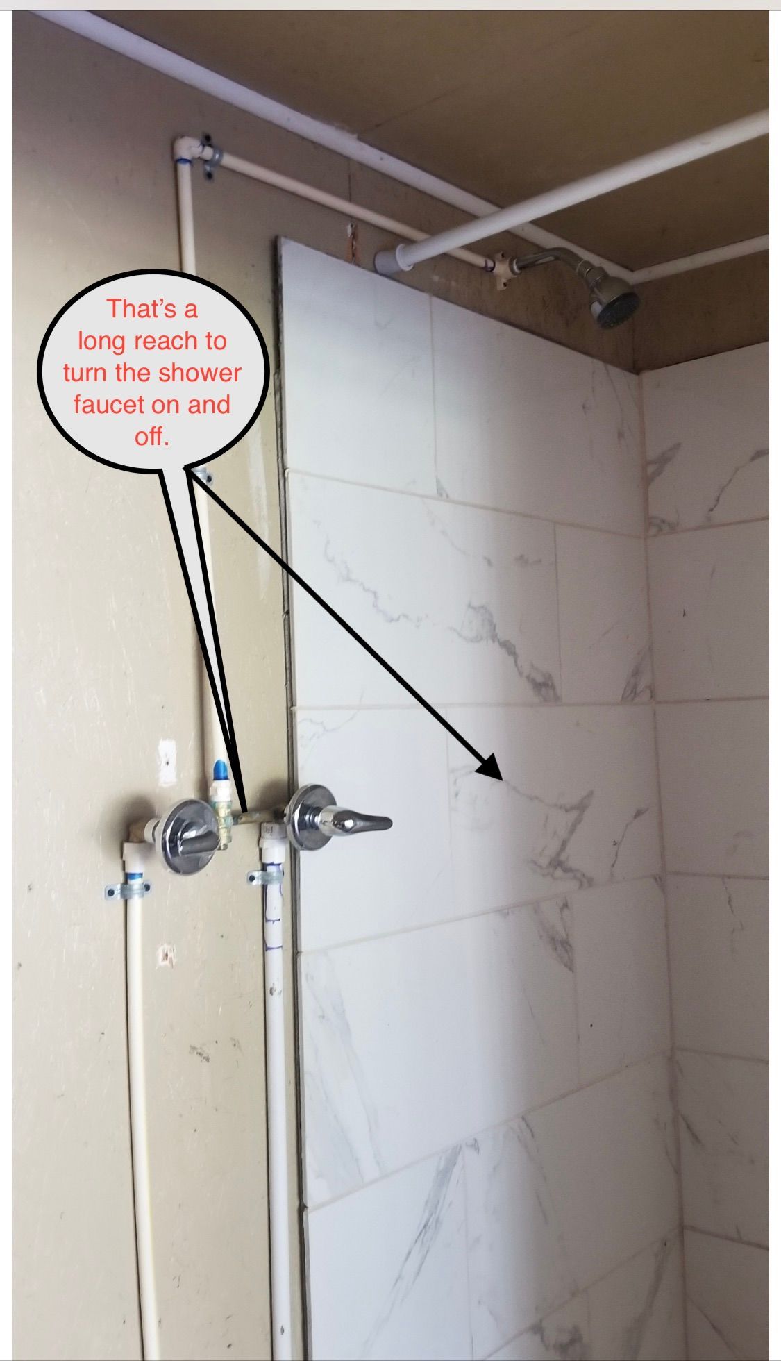 Bathroom wall with shower pipes and a red annotation pointing to a cracked tile corner.