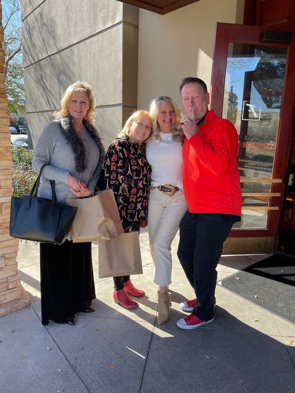 Four people outside a building. Two women in light colors, two in darker, one red jacket.
