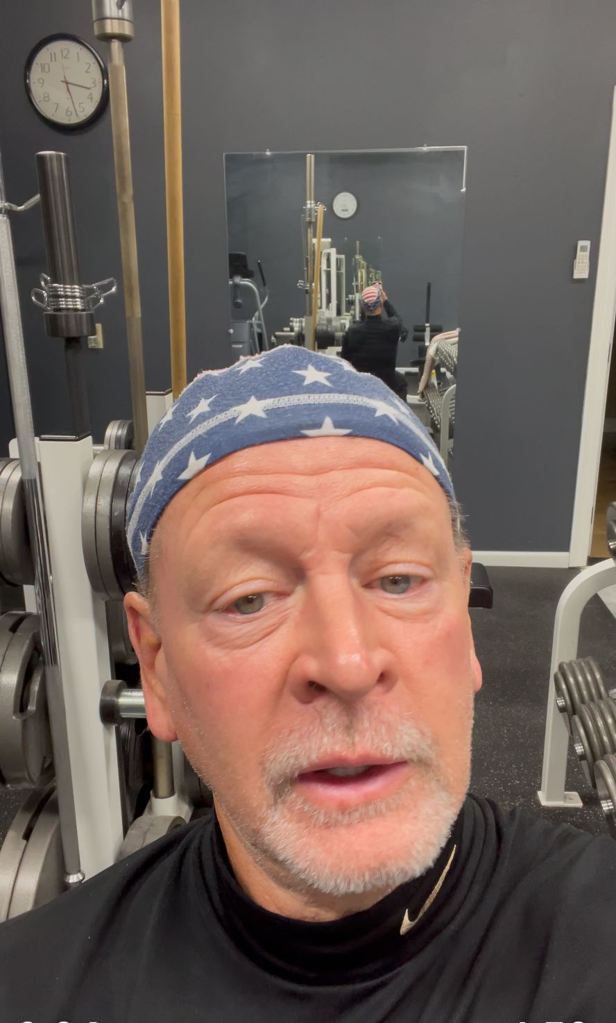 Man in gym wearing blue bandana and black shirt.