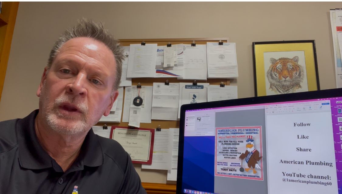 Man speaks into the camera, poster on a monitor, corkboard in background.