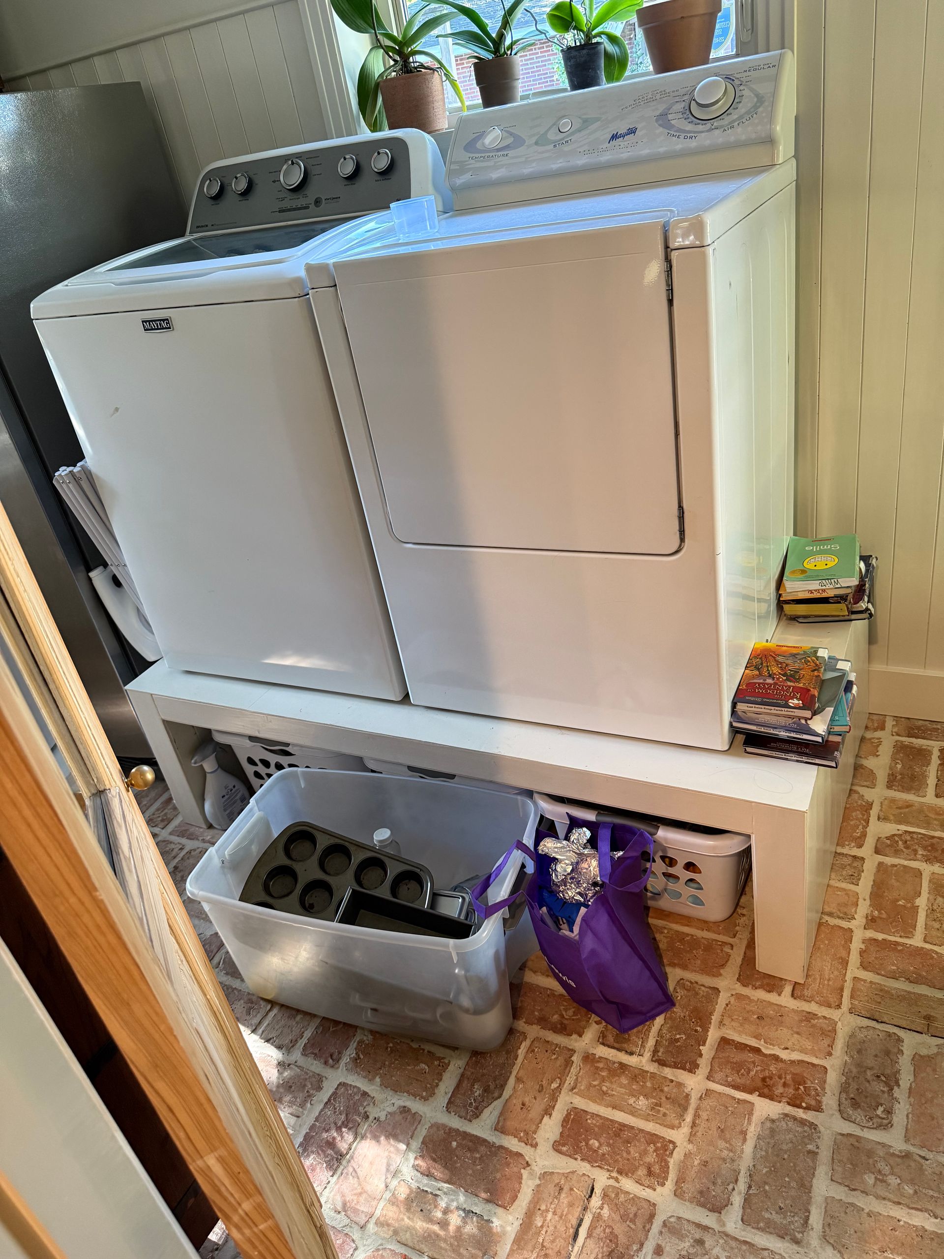 Laundry area with a washer, dryer, and shelves holding detergent and storage bins