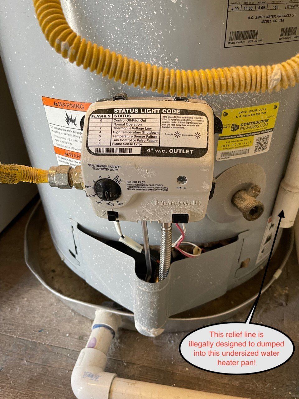 Gas water heater with control panel and gas line, near a drainpipe.