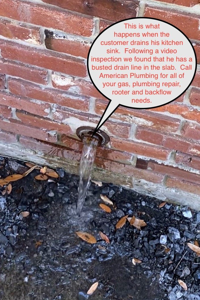 Brick wall with a pipe leaking water onto dark ground, next to a speech-bubble sign.