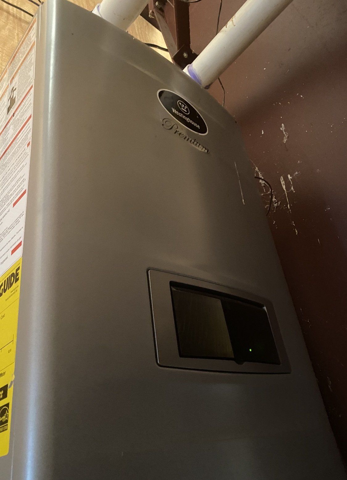Gray water heater in a utility room with a yellow energy efficiency label.
