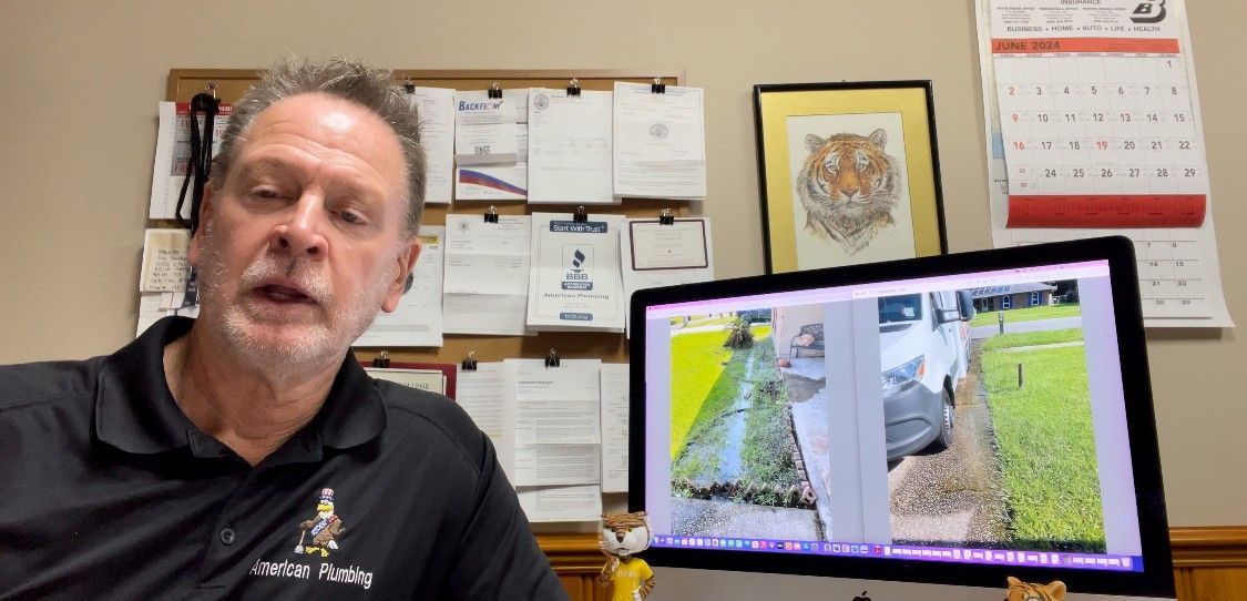 Man speaking, desktop monitor displaying outside images; office setting with artwork, papers, and calendar.