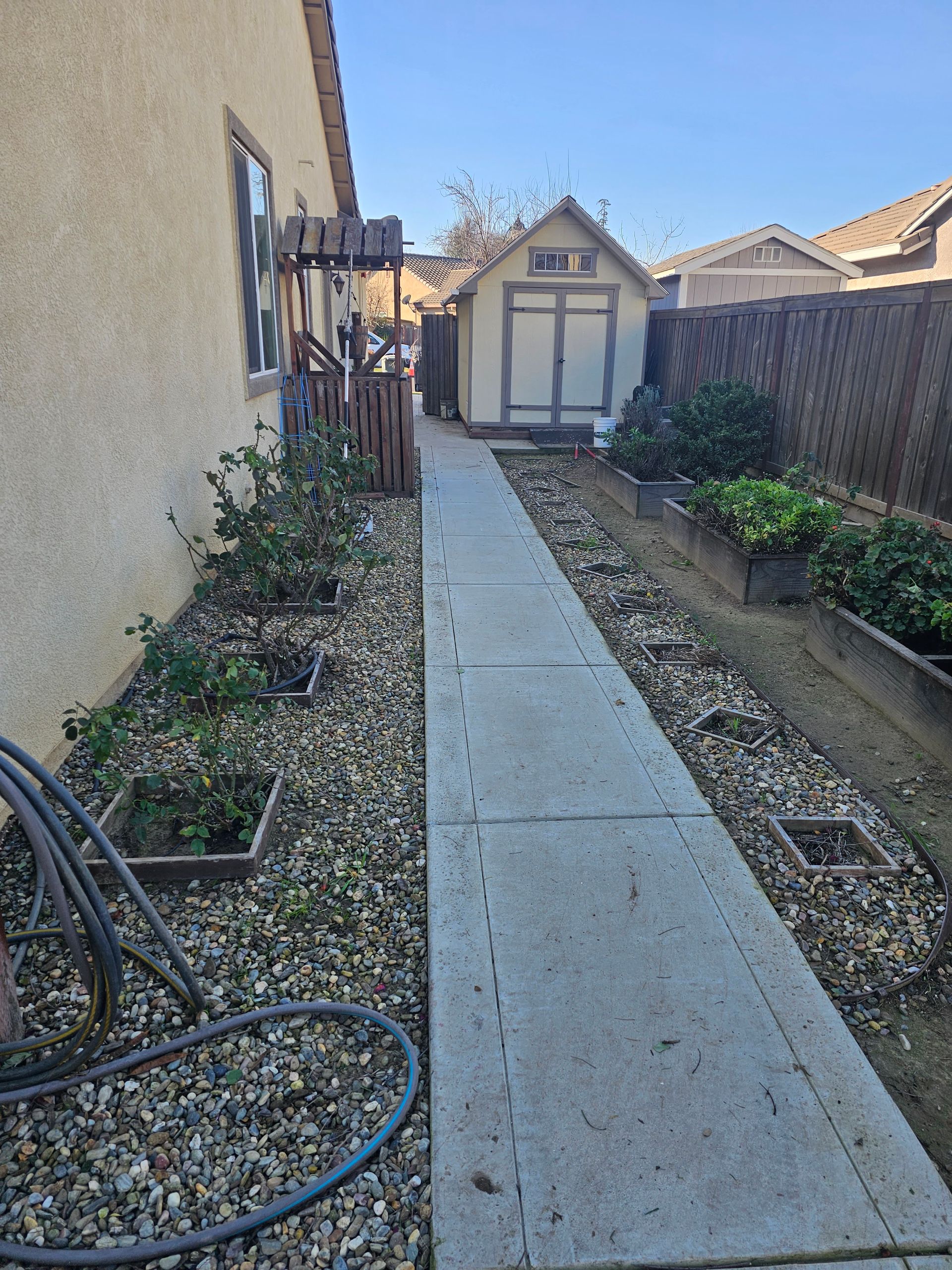 A sidewalk leading to a shed in the backyard of a house