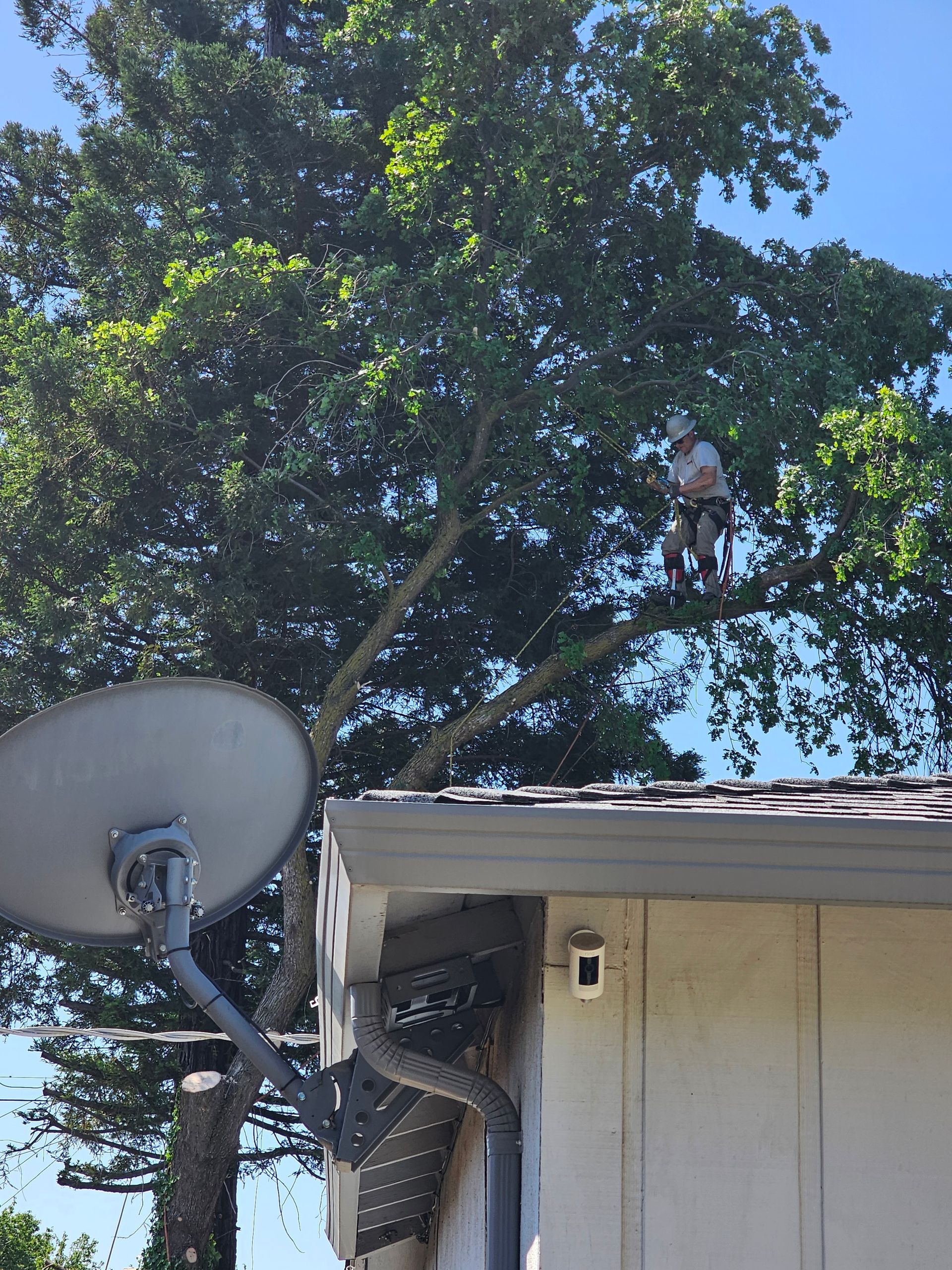 A man is standing on the roof of a house next to a satellite dish