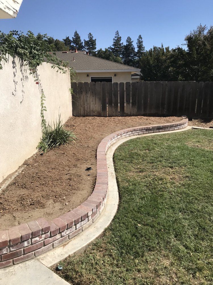 A backyard with a brick wall and a fence.