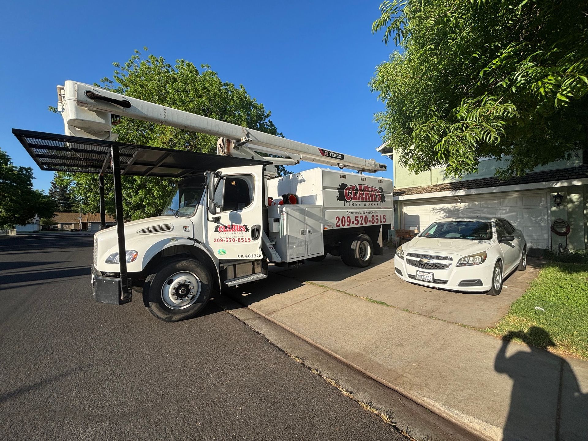 A white truck is parked on the side of the road next to a white car.