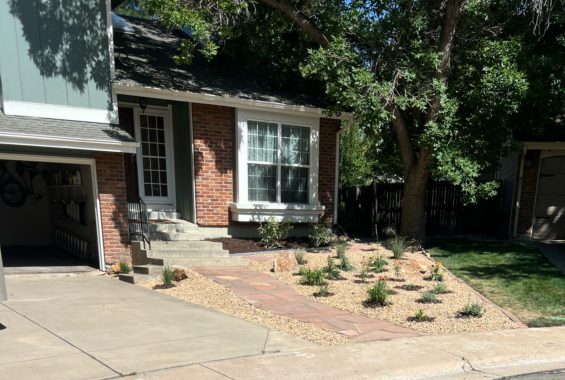 House exterior with brick accents, small yard with path and plants, stone border.