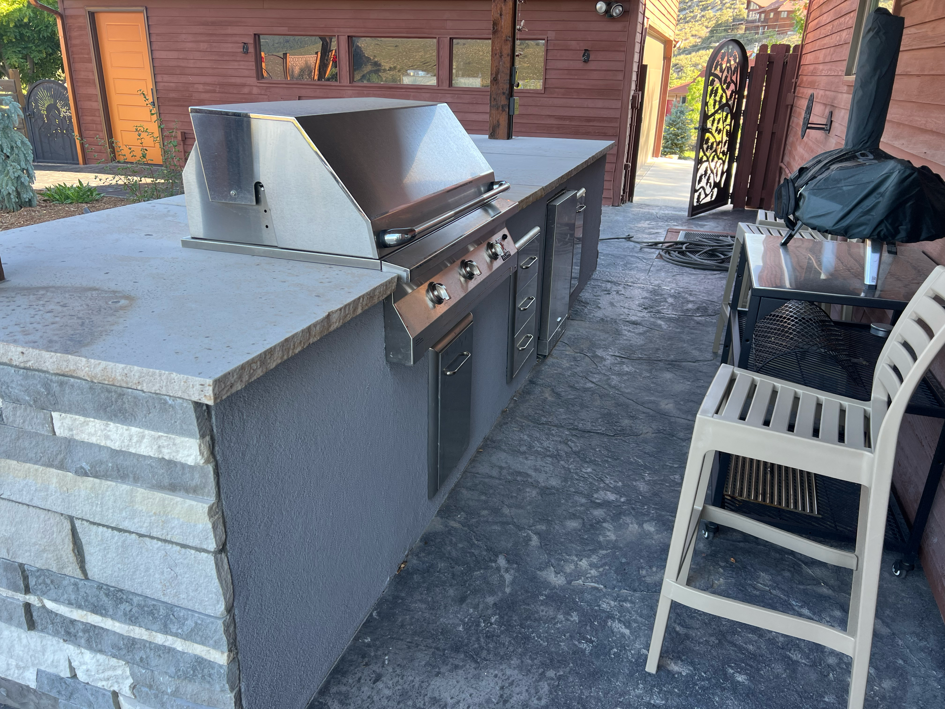 Outdoor kitchen with a stainless steel grill, cabinets, and stone facade.