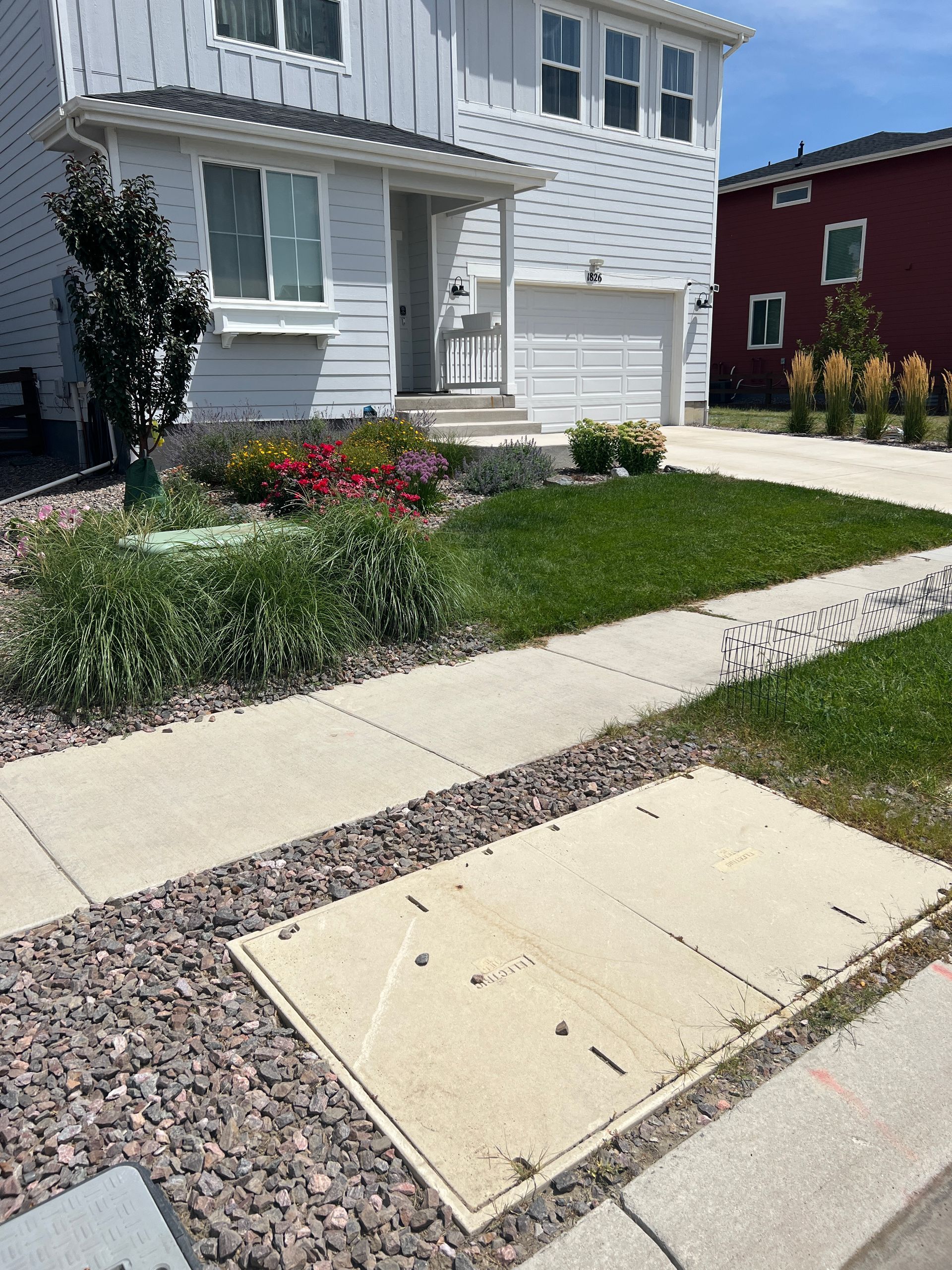 Two-story light blue house with a landscaped front yard and concrete sidewalk.