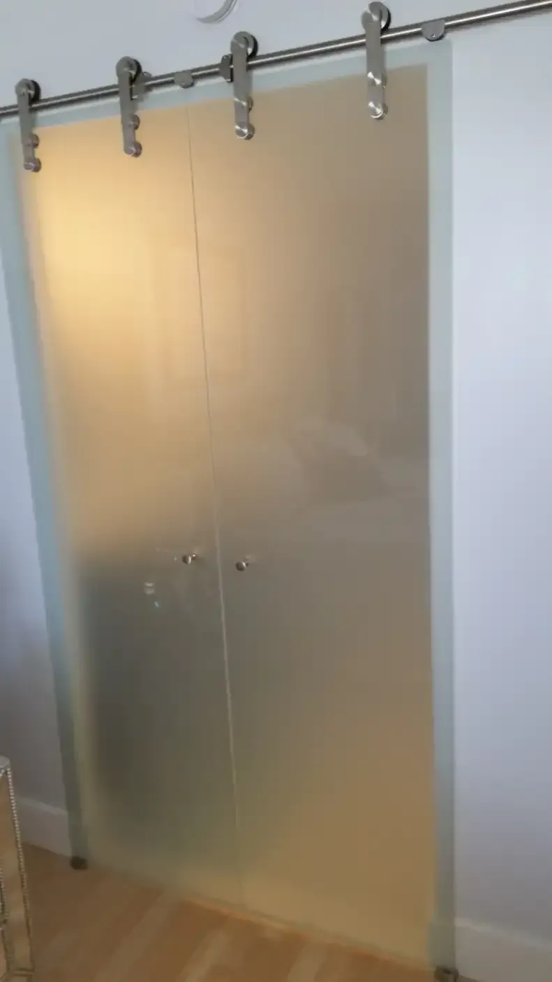 A sliding glass door with a stainless steel railing in a room.