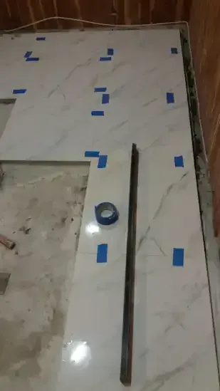A person is laying tiles on the floor in a bathroom.