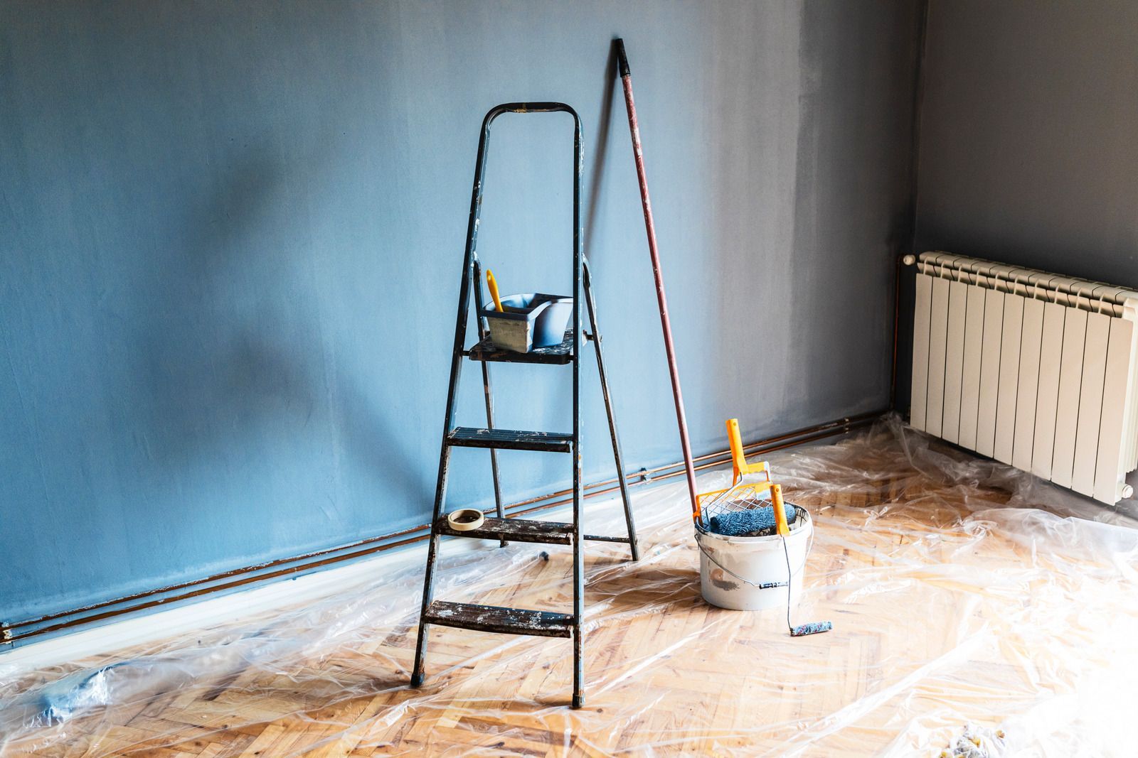 A room is being painted with a ladder and a bucket of paint.