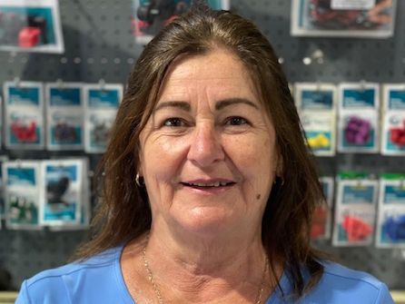 Woman smiling in a blue shirt in front of a display wall with colorful packaged items