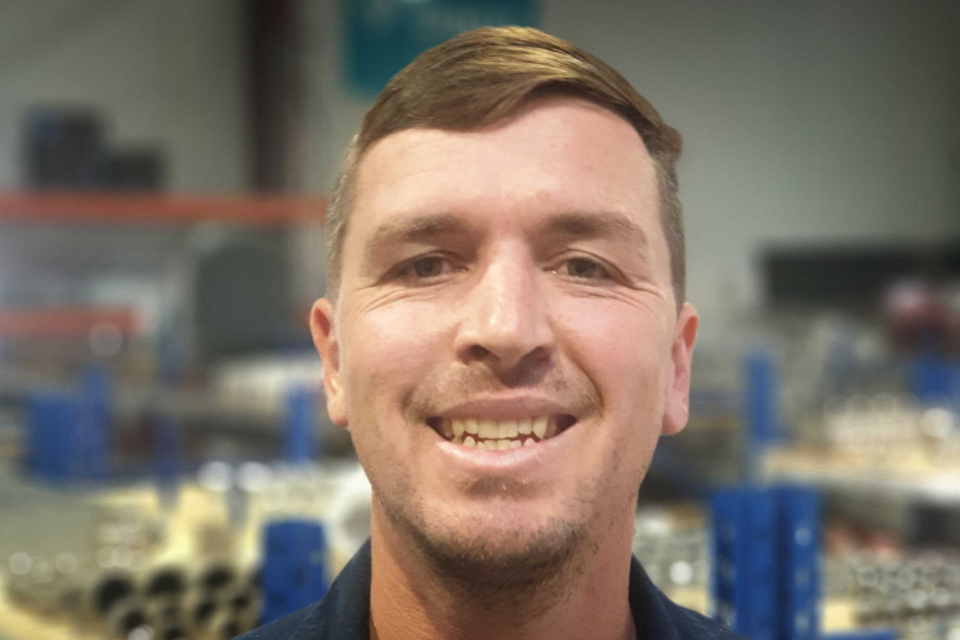 Smiling man in a workshop with blurred machinery in the background