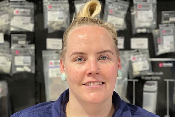 Person smiling in a store aisle, with rows of packaged items in the background