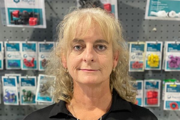 Person with blond hair standing in front of a wall of packaged products in a store.