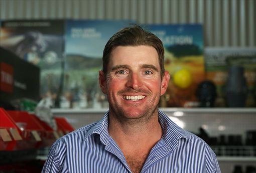 Smiling man in a blue striped shirt standing in a store aisle