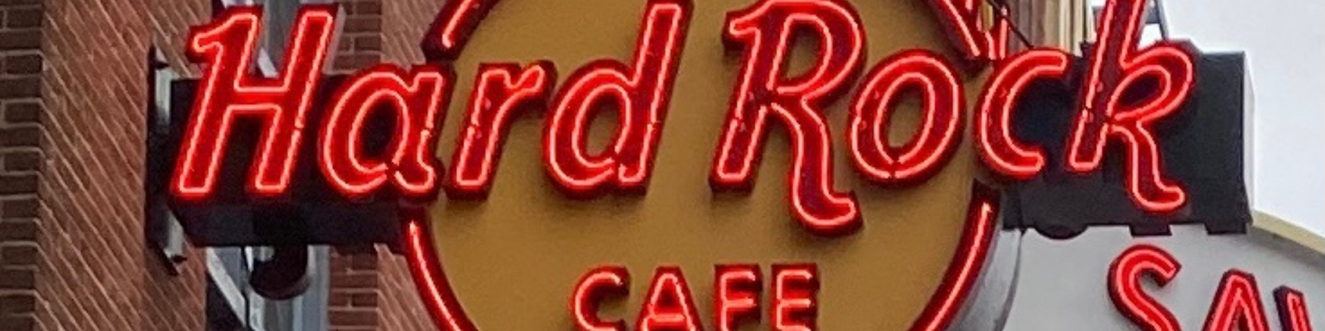 A neon sign for hard rock cafe on a brick building