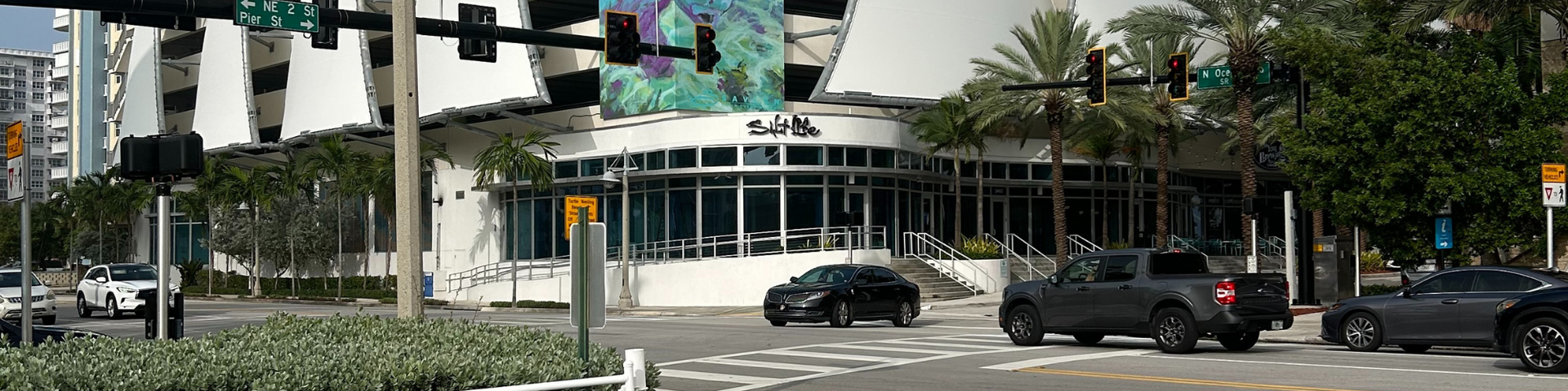 A group of cars are driving down a street in front of a building.