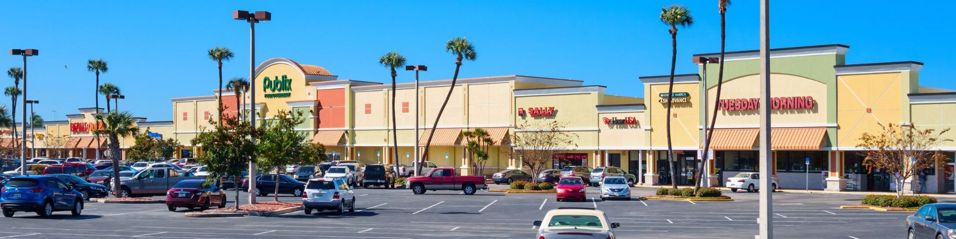 A lot of cars are parked in front of a shopping center