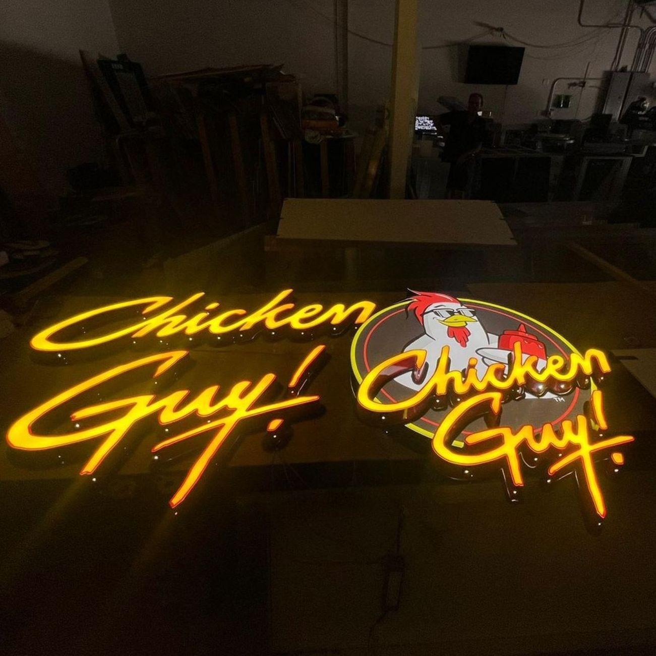 A neon sign for chicken guy is lit up in a dark room