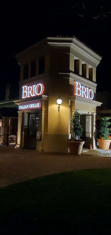 A brio restaurant is lit up at night.