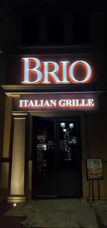 A sign for brio italian grille is lit up at night