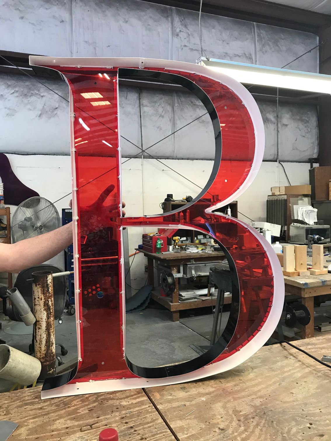 A large red letter b is sitting on top of a wooden table.