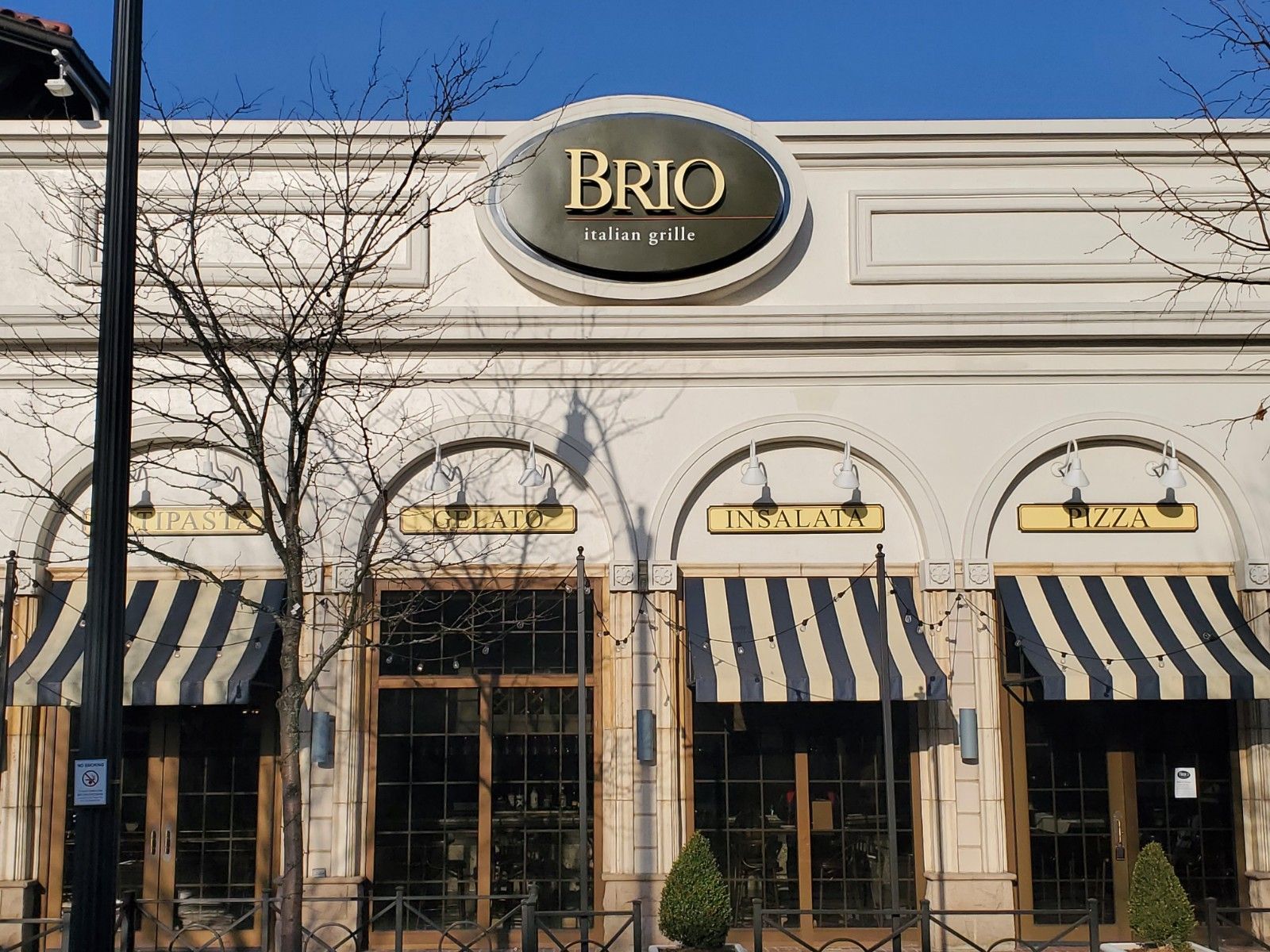 The front of a brio restaurant with striped awnings