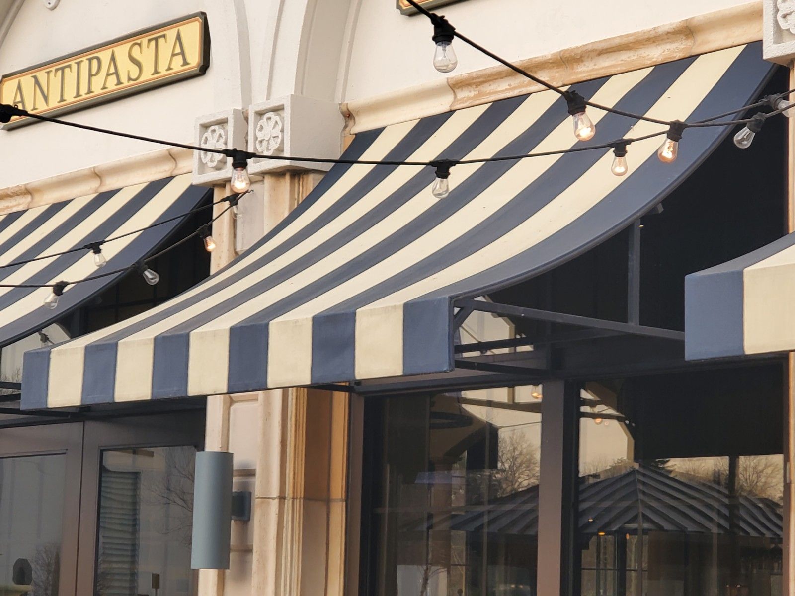 A restaurant with a striped awning and a sign that says antipasta