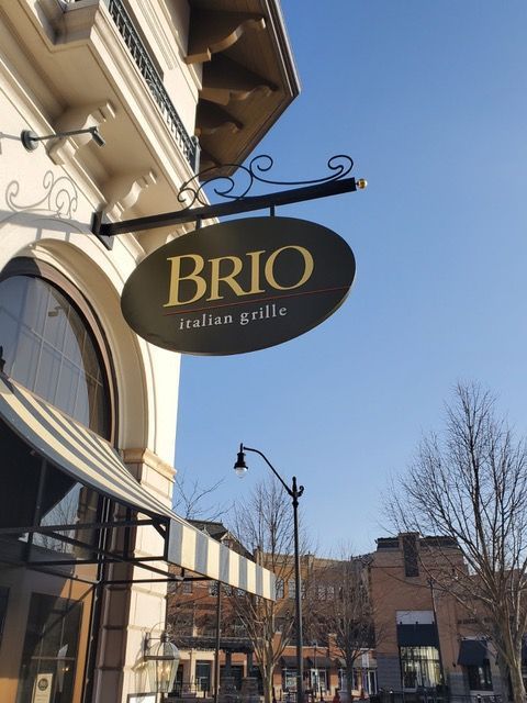 A sign for brio italian grill hangs from the side of a building