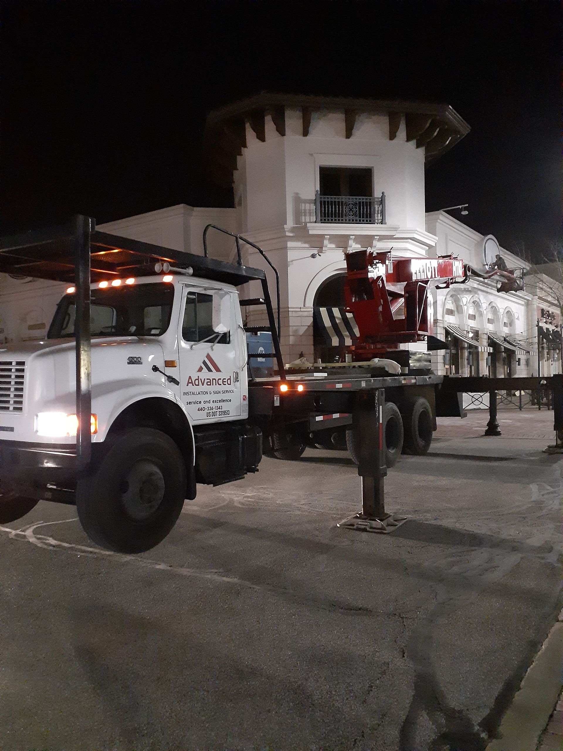 A white truck is parked in front of a building at night