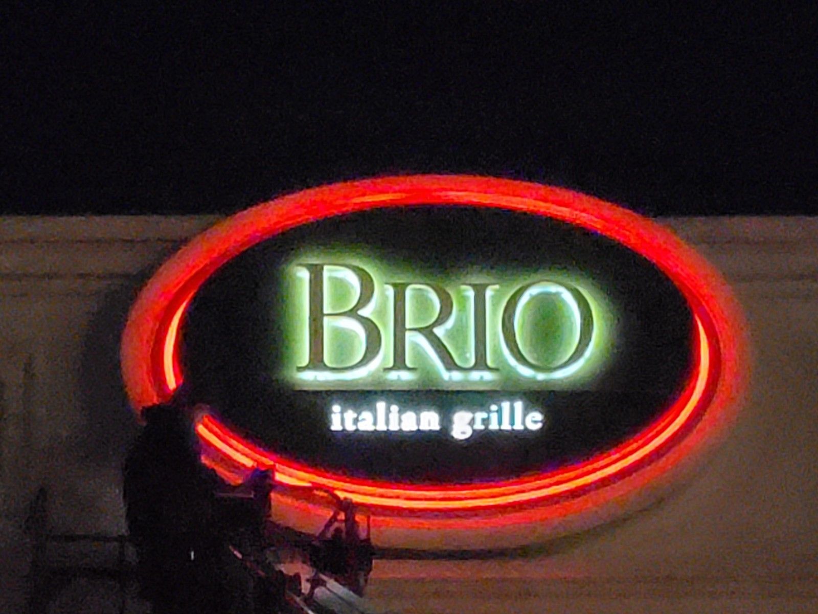 A neon sign for brio italian grille is lit up at night