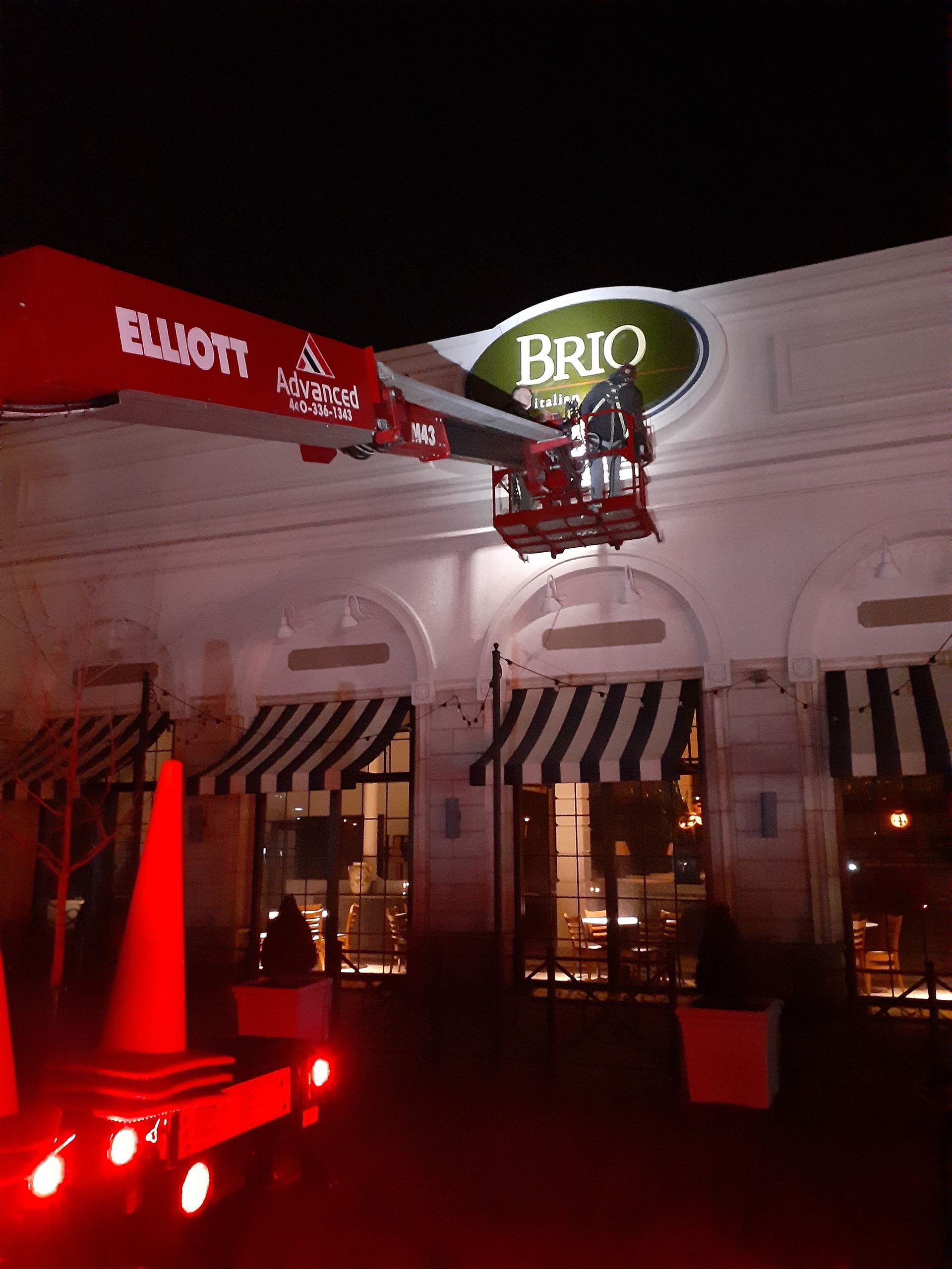 A crane is lifting a sign that says brio on it