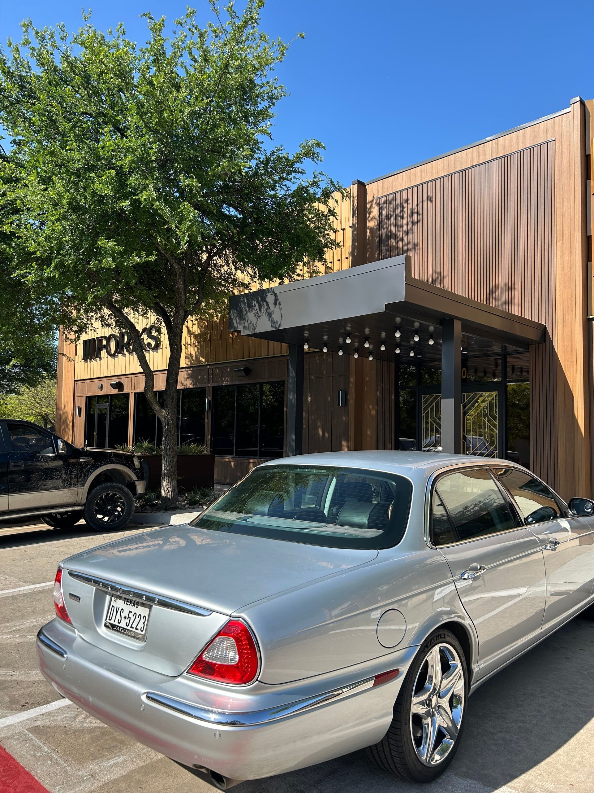 A silver car is parked in front of a building.