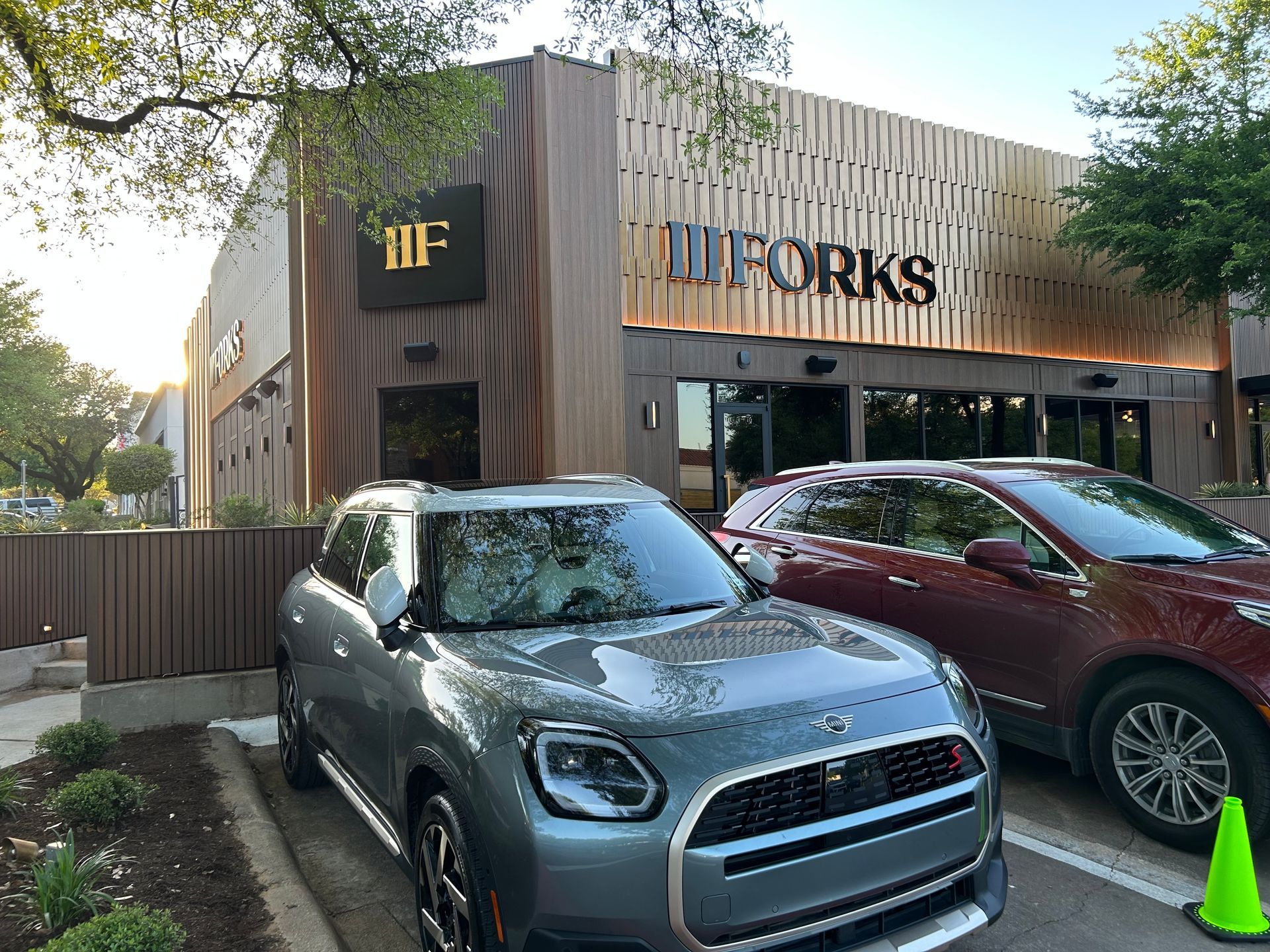 Two cars are parked in front of a building that says forks.