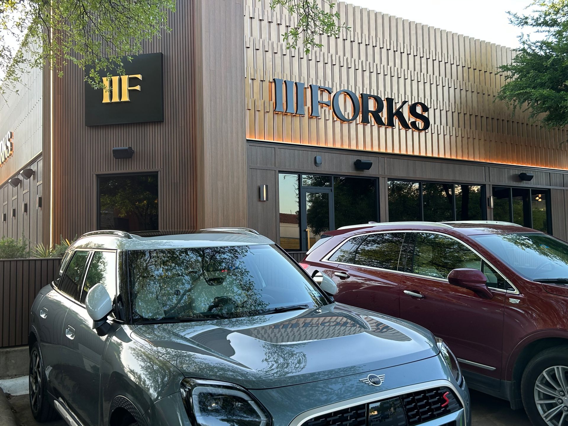 Two cars are parked in front of a building that says forks