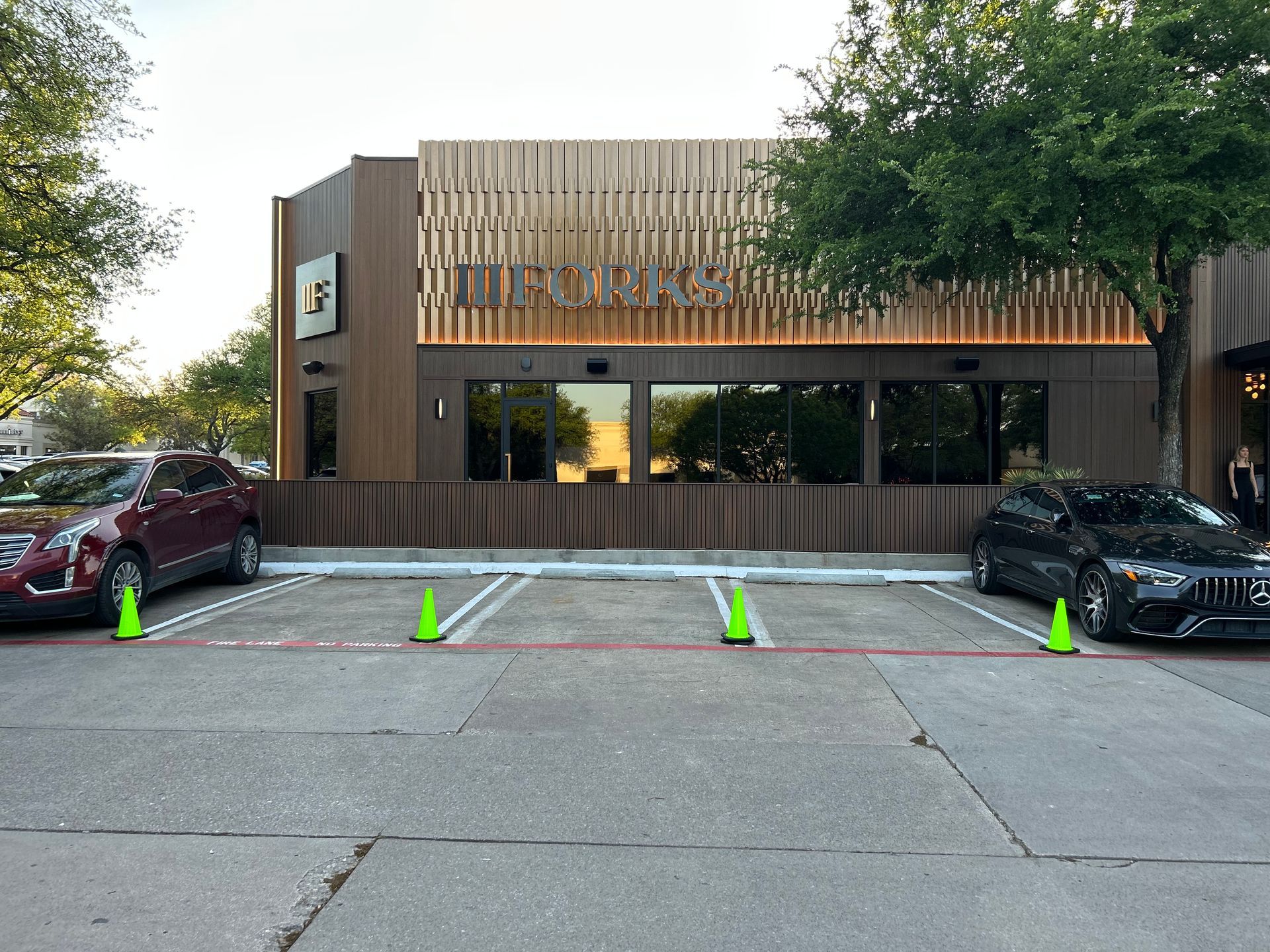 Two cars are parked in a parking lot in front of a building.