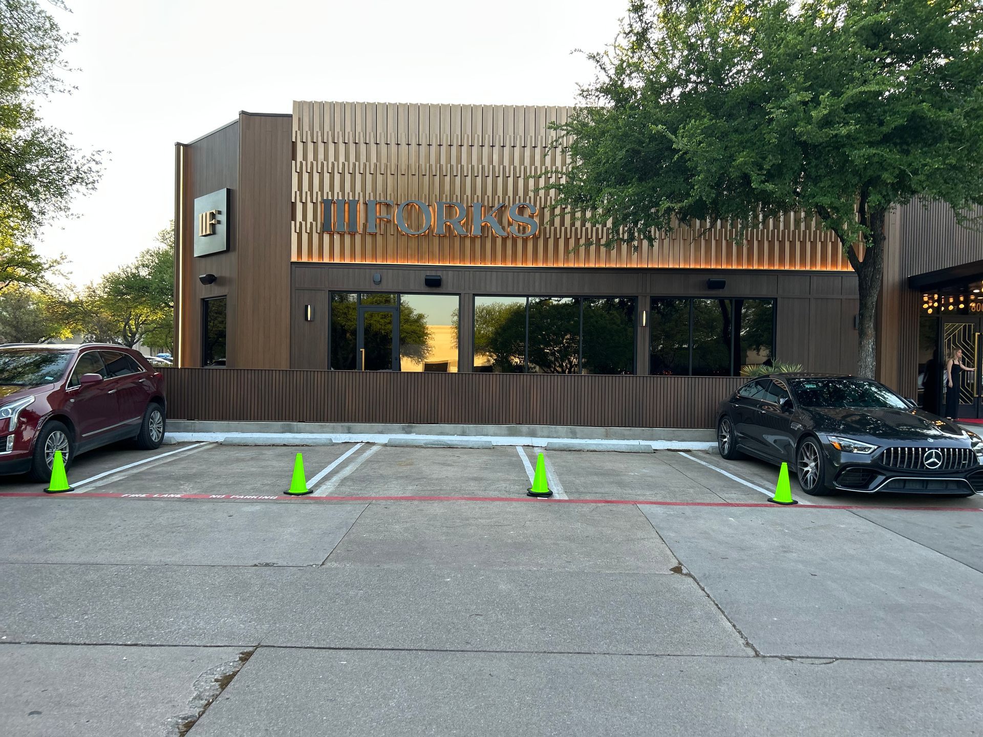 Two cars are parked in a parking lot in front of a building.